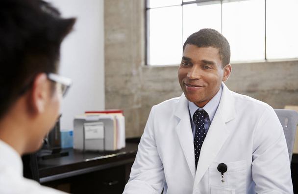 Smiling mixed race male doctor in consultation with patient - Foto, imagen