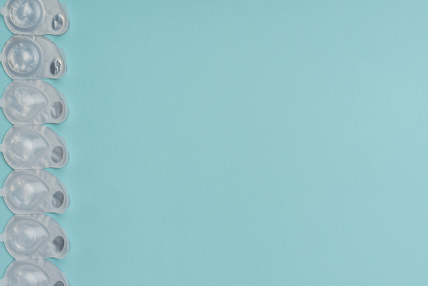Düzenlenmiş mavi zemin üzerine beyaz kaplarda kontakt lensler ile düz lay - Fotoğraf, Görsel