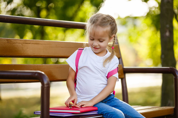 本でベンチに座っているバックパックの小さな女子高生 - 写真・画像