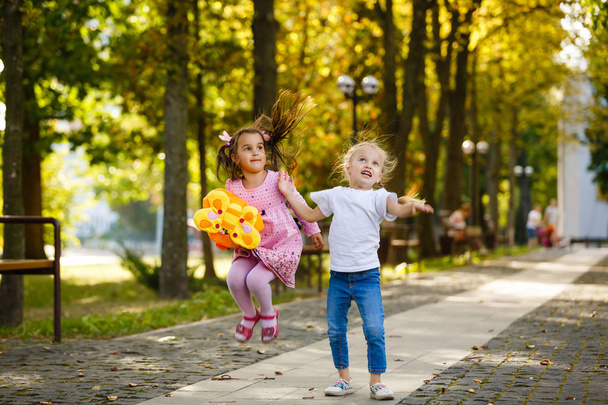 two happy little schoolgirls jumping in park - Foto, immagini