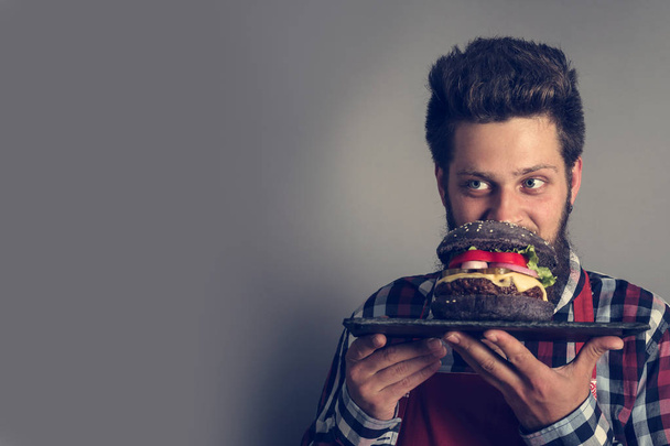 Muž čichající čerstvé já z černého hamburgeru zblízka - Fotografie, Obrázek