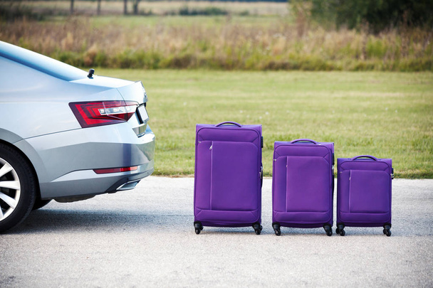 τρεις βαλίτσες δίπλα από το αυτοκίνητο στο δρόμο - Φωτογραφία, εικόνα