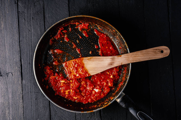 Classic homemade tomato sauce in the pan on a wooden chopping board on brown background, top view. Pasta, pizza tomato sauce. Vegetarian food - Photo, Image