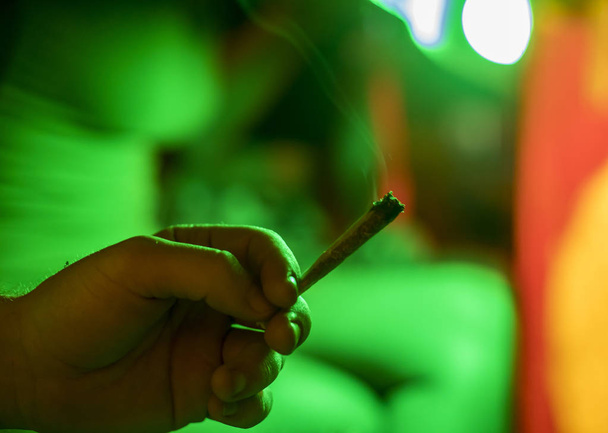 Mano con una marihuana en cigarrillo conjunto sobre fondo verde
 - Foto, Imagen
