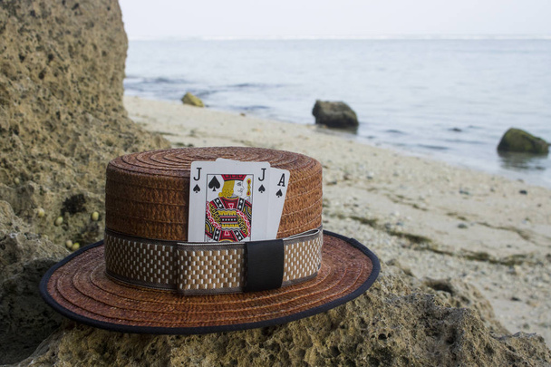 bruin boater hoed met blackjack kaarten op strand - Foto, afbeelding