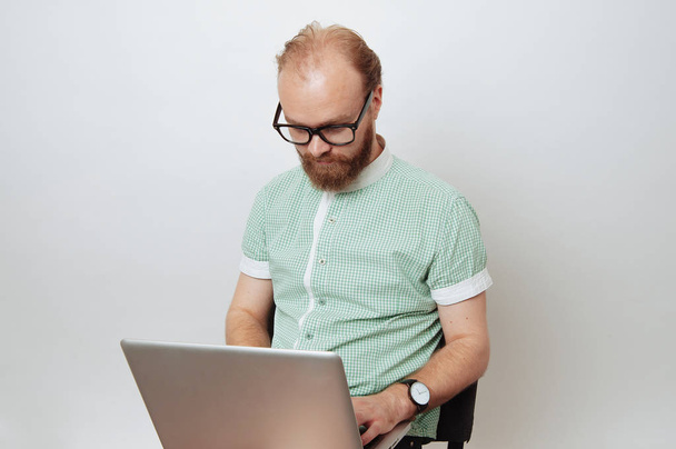 Barbuto hipster uomo indossare occhiali e lavorare al computer portatile su sfondo bianco
 - Foto, immagini