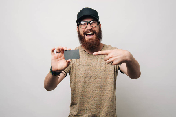 Happy bearded man pointing at credit card - Photo, Image