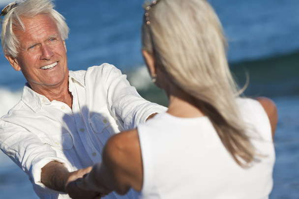Heureux couple âgé dansant tenant la main sur une plage tropicale
 - Photo, image
