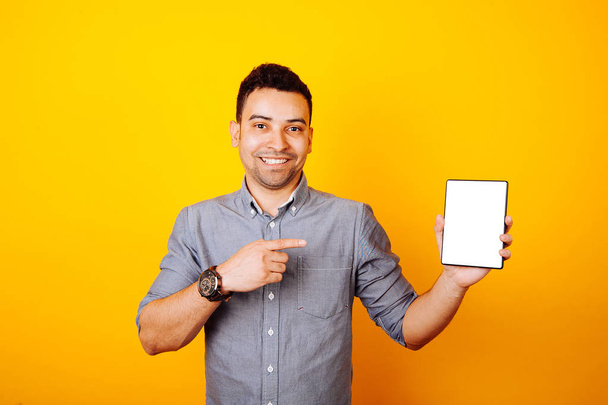 vrolijke jongeman wijzend op wit scherm tablet - Foto, afbeelding