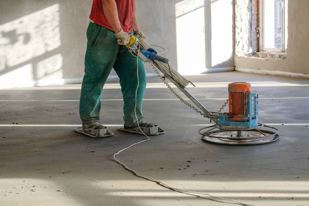 the workers grind the concrete floor at the construction site - Fotó, kép