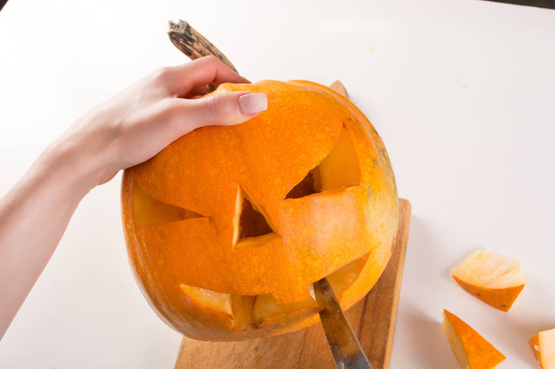 Orangenkürbis schnitzen für den Halloween-Feiertag. Mädchen Hand mit Messerschnitten und bereiten Jack o Laternen. Nahaufnahme, selektiver Fokus - Foto, Bild