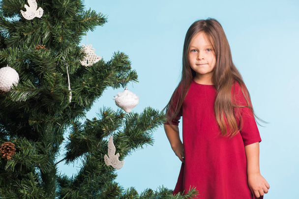 Little girl with christmas tree on blue background - Photo, image