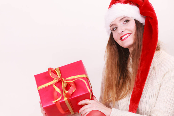 Gorgeous woman wearing santa claus hat holding red big gift box with ribbon. Xmas, happiness, winter and people concept. - 写真・画像