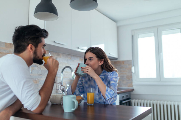 Photo of young couple starting the day together with coffee in the kitchen. - Фото, изображение