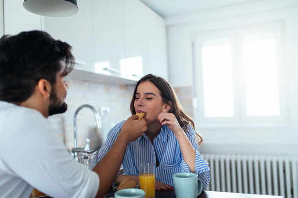 Portrait of a young couple enjoying having breakfast together at home. - Foto, Imagem