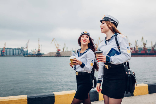 Kaksi merijalkaväen naisopiskelijaa kävelee meritse univormussa. Ystävät kävelevät, puhuvat ja juovat kahvia
 - Valokuva, kuva