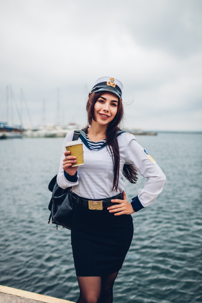 Student van vrouw van Marine Academie koffie drinken door zee dragen van uniform. Meisje lopen in de zeehaven van Odessa op pier - Foto, afbeelding