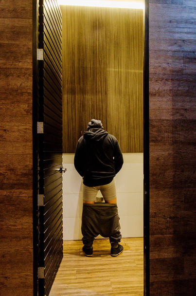 Stehender Mann pinkelt in Toilette auf Urinal oder Inkontinenzkonzept - Foto, Bild