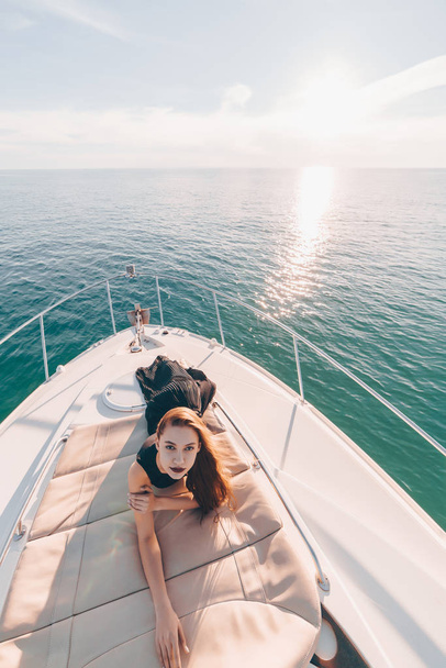 a luxurious attractive girl in black clothes lies on a yacht, poses, enjoys a vacation - Foto, Imagem