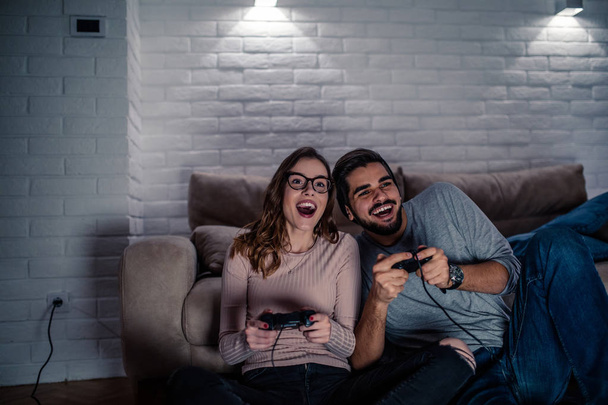 Photo of young couple playing video games at home at night. - Foto, Bild