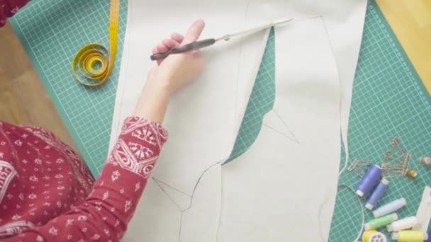 Middle-age woman hands with scissors cutting paper template. Handmade cloth. - Footage, Video