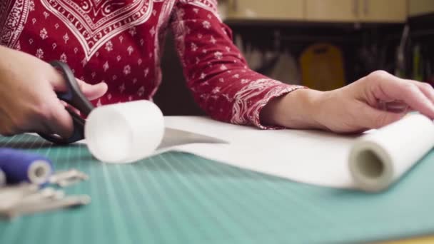 Keski-ikäinen nainen kädet sakset leikkaamalla paperi kuvio. Käsintehdyt vaatteet
. - Materiaali, video