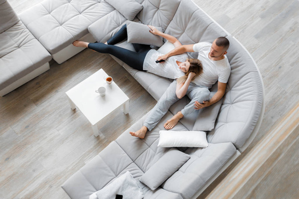 Young couple resting on sofa at home. Family relaxation lifestyle - Фото, изображение