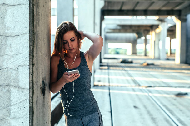 Woman using mobile phone for setting running play list. - Foto, immagini
