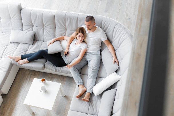 Young couple resting on sofa at home. Family relaxation lifestyle - Fotografie, Obrázek