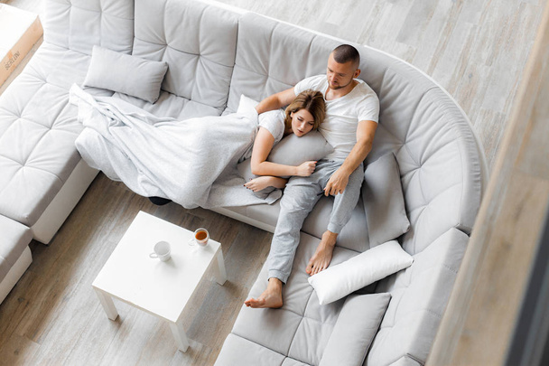 Young couple resting on sofa at home. Family relaxation lifestyle - Zdjęcie, obraz