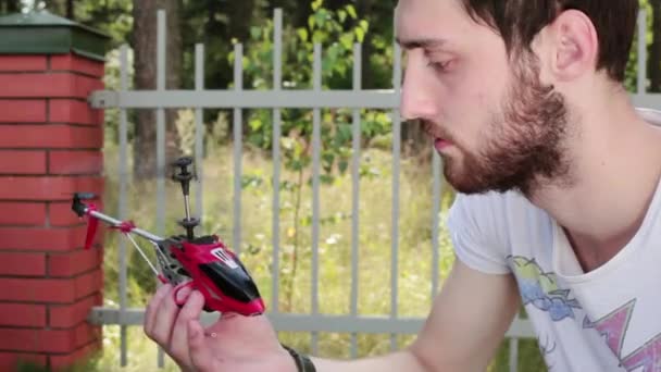 In daylight man holds in hands turned-on nano helicopter then turns it off. - Footage, Video
