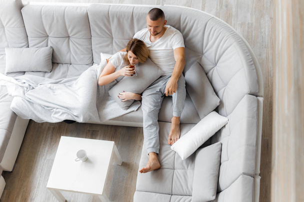 Young couple resting on sofa at home. Family relaxation lifestyle - Fotoğraf, Görsel