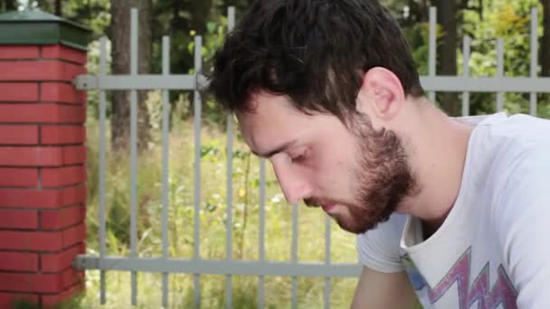 Young bebaarde man opent leeg blauw fluweel trouwring vakje naast hek - Video
