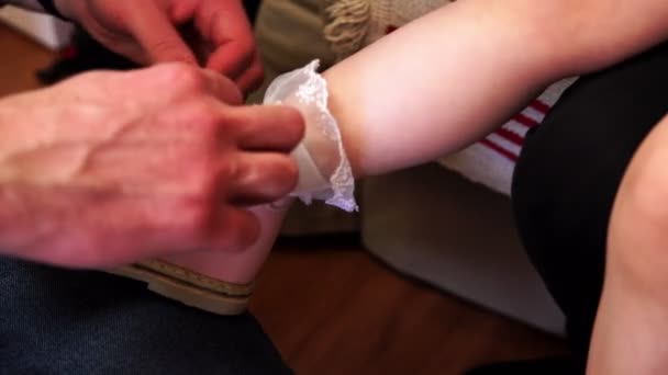 Отец одевает сандалии на свою маленькую дочь
. - Кадры, видео