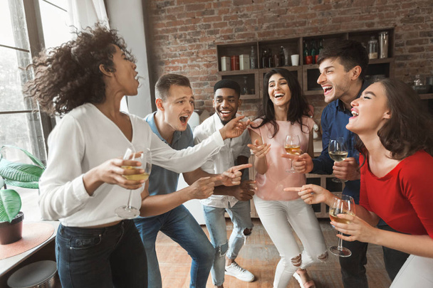 Enthousiast jonge mensen zingen en drinken thuis partij - Foto, afbeelding