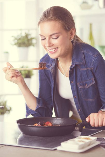Young woman cooking healthy food holding a pan with vegetables is it. Healthy lifestyle, cooking at home concept - Fotografie, Obrázek