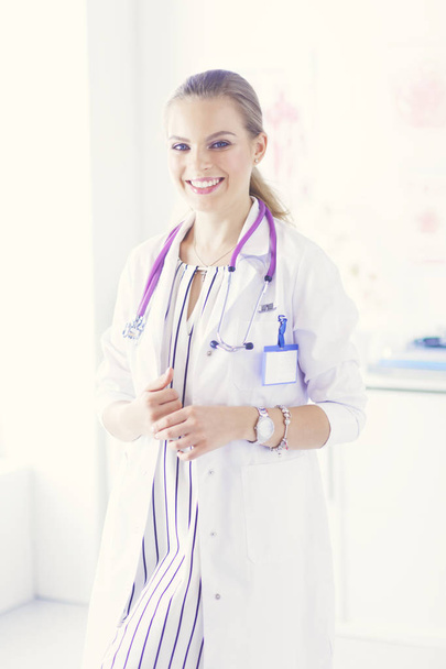Smiling female doctor with a medical stethoscope in uniform standing - Foto, afbeelding