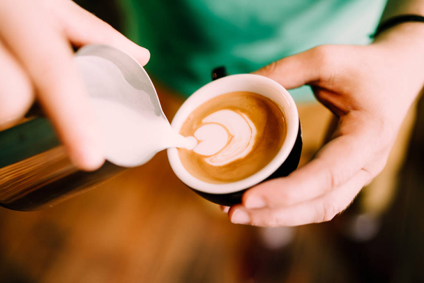 Barista man creating latte art with cappuccino at local bistro, pub and cafe shop - Фото, изображение