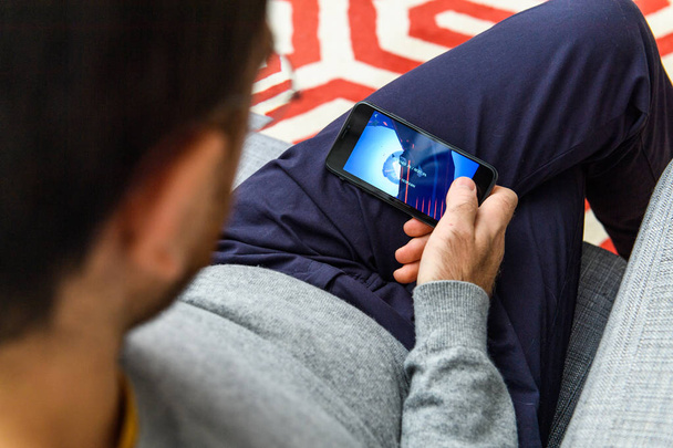 LONDON, UK - SEP 21, 2018: Man using the new Apple iPhone Xs with the immense OLED retina display and a12 bionic chip, looking over the app application RPG game play - 写真・画像