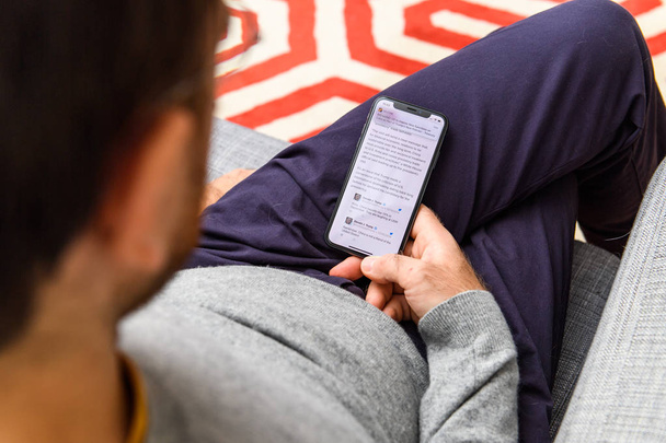 LONDRES, Reino Unido - SEP 21, 2018: Hombre usando el nuevo Apple iPhone Xs con la inmensa pantalla OLED retina y un chip biónico a12, mirando por encima de la aplicación de propaganda sputnik sitio de noticias falsas
 - Foto, imagen