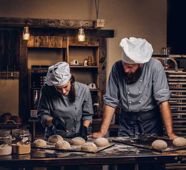 Chef ensinando seu assistente a assar o pão em uma padaria
. - Foto, Imagem
