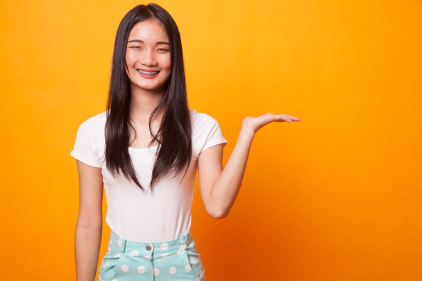 Beautiful young Asian woman show palm hand on bright yellow background - Foto, Imagem