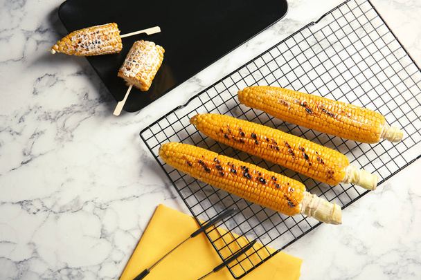 Cooling rack with grilled corn cobs on marble background, top view - Foto, afbeelding