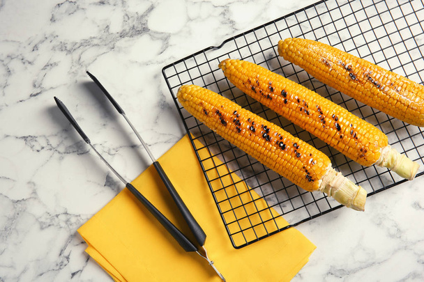 Cooling rack with grilled corn cobs on marble background, top view - Photo, Image