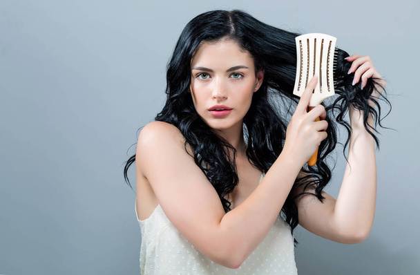 Beautiful young woman holding a hairbrush - Фото, зображення