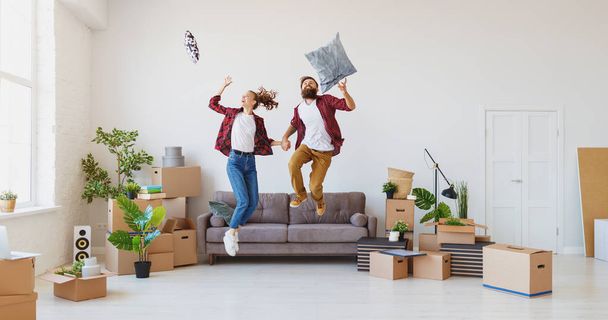 a happy young married couple moves to new apartment and laughing,  jump, fight pillow - Foto, Bild
