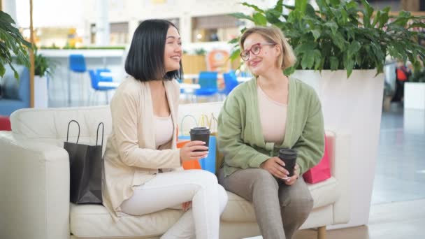 Két nő meg szórakozás közben a bevásárlóközpontban vásárlási, miután egy kis szünetet, ivó kávé és beszél - Felvétel, videó