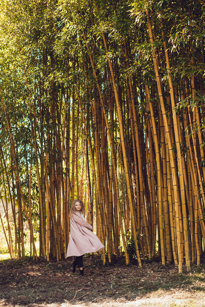 elegáns fiatal lány pózol egy bambusz fának a parkban, pihenő - Fotó, kép