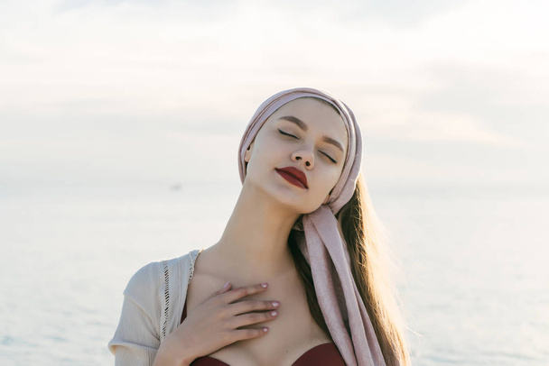 an attractive, tranquil girl with red lipstick closed her eyes, enjoys sea voyage - Fotoğraf, Görsel