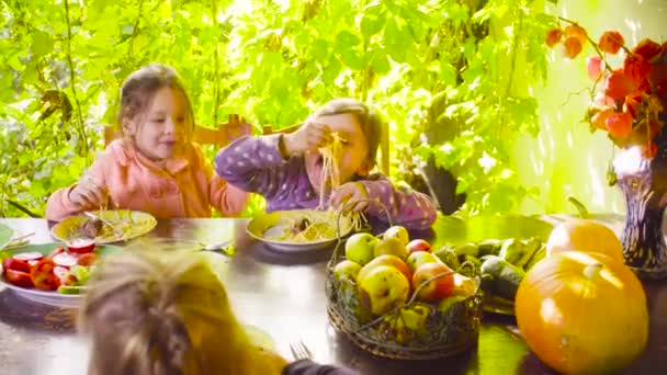 İki yaramaz kız masada oturan ve makarna ve kızarmış sosis yeme - Video, Çekim